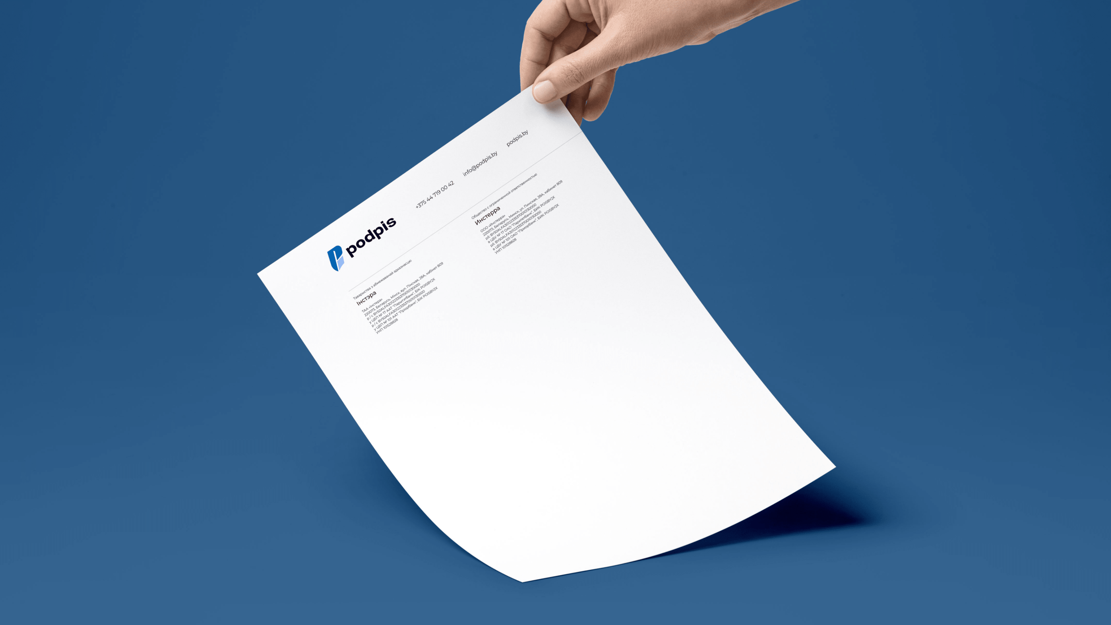 A hand holds a printed resume on a blue background. The resume, featuring the Paddlejs logo and a Podpis.by mention in the top left corner, has text sections below, while most of the page remains blank or minimally filled.